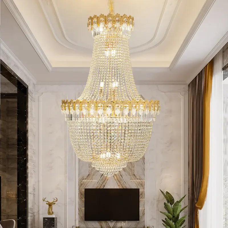 Decorbites crystal chandelier with gold-toned metalwork and cascading clear crystal prisms in luxury duplex stairwell