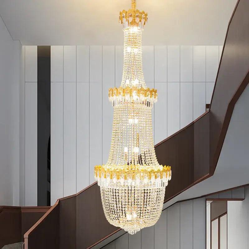 Decorbites crystal chandelier with gold-toned metal and glass prisms in luxury duplex hotel living room stairwell design