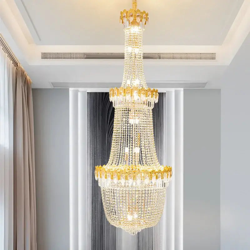 Luxurious gold-toned decorbites crystal chandelier with multiple tiers of clear crystals for duplex hotel stairwell design