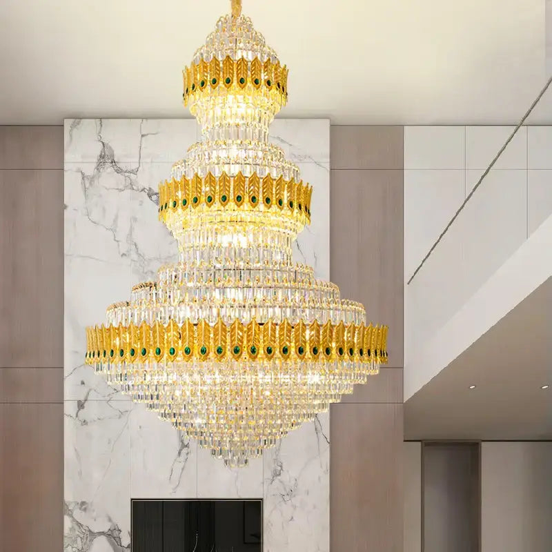 Golden tiered decorbites crystal chandelier with clear crystal droplets and green gemstone accents for high-end living rooms