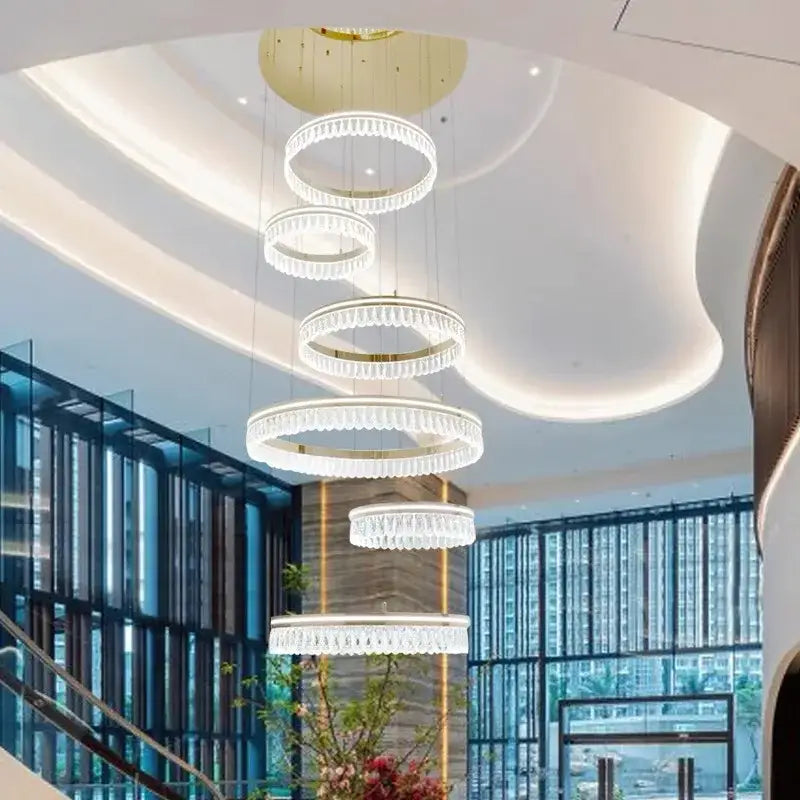 A modern multi tiered decorbites crystal chandelier with cascading crystal rings and a golden ceiling fixture for luxury lighting