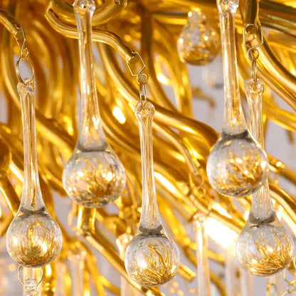 Golden decorbites crystal chandelier with clear glass teardrop pendants and intricate gold-toned metalwork lighting fixture