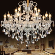 A decorbites crystal chandelier with multiple tiers of teardrop crystals and silver arms illuminated by warm bulbs