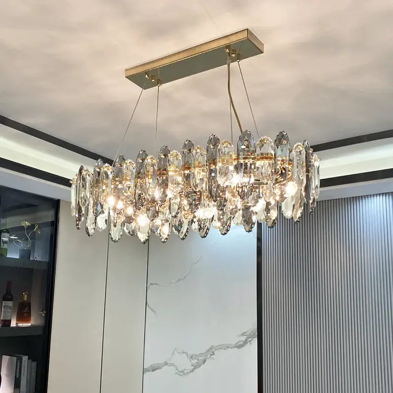 A modern decorbites crystal chandelier with a gold metal frame and clear crystal teardrop pendants for living spaces