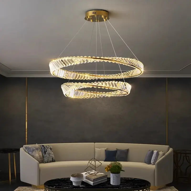 A modern decorbites crystal chandelier featuring double gold-toned metal rings and clear crystal accents for living rooms