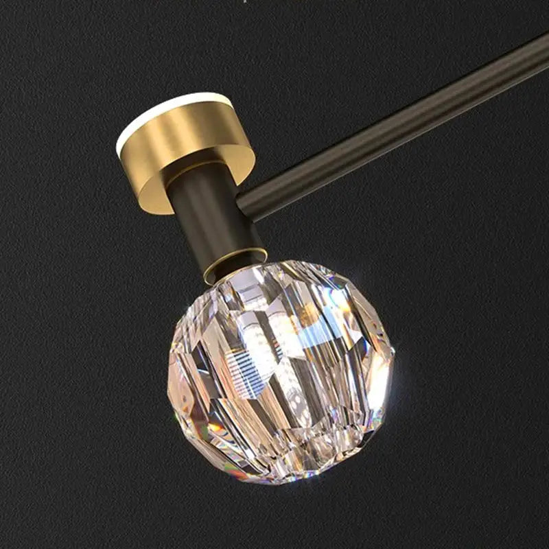 A faceted crystal globe with gold-toned metal base and bronze arm in decorbites crystal chandelier pendant light