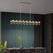 Gold-toned decorbites crystal chandelier featuring linear design with multiple crystal globe bulbs for living and dining room