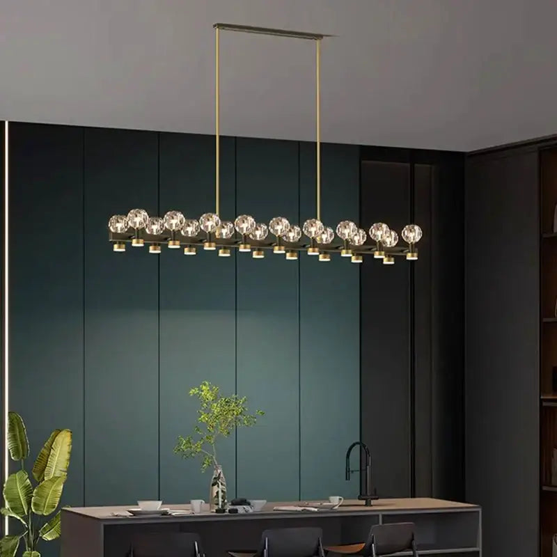 Gold-toned decorbites crystal chandelier featuring linear design with multiple crystal globe bulbs for living and dining room