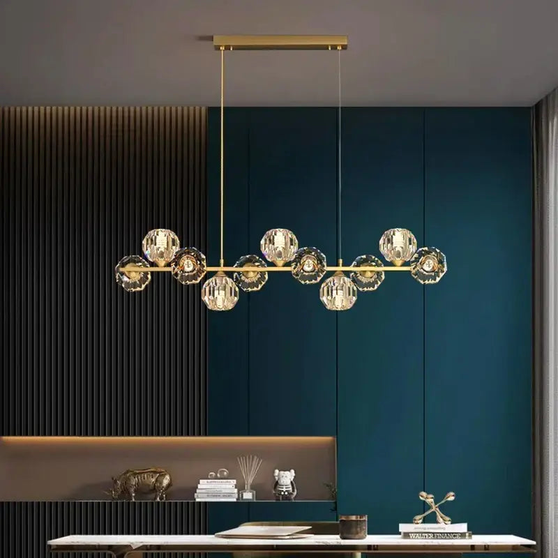Gold-toned decorbites crystal chandelier with faceted crystal globe shades on horizontal bar for living and dining room
