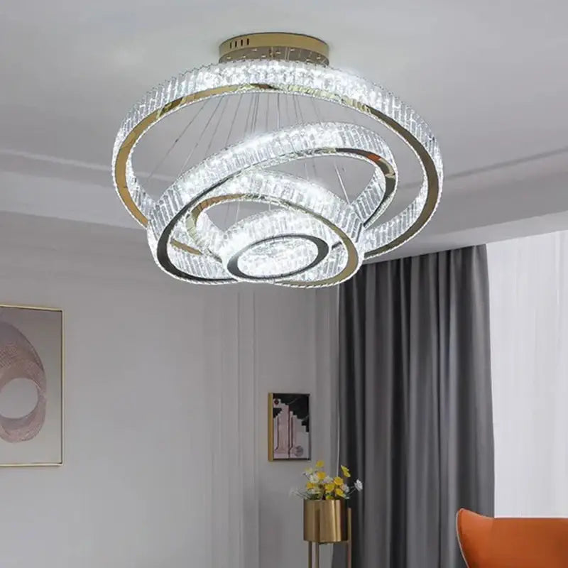 A modern decorbites crystal chandelier with gold-toned rings and clear crystals for living room and staircase lighting
