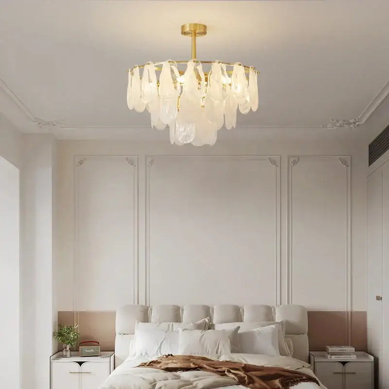 A modern gold-toned metal decorbites crystal chandelier with translucent leaf-shaped glass shades for living rooms