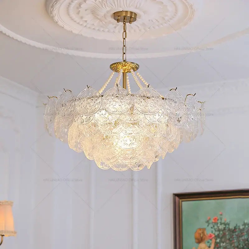 Elegant gold-toned decorbites crystal chandelier with layered etched crystal petals and pearl-like beads for modern decor