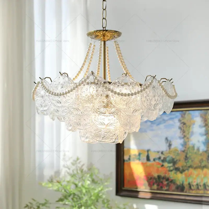 Elegant decorbites crystal chandelier with floral etchings, cream pearl strands, and brass-finished frame for home decor