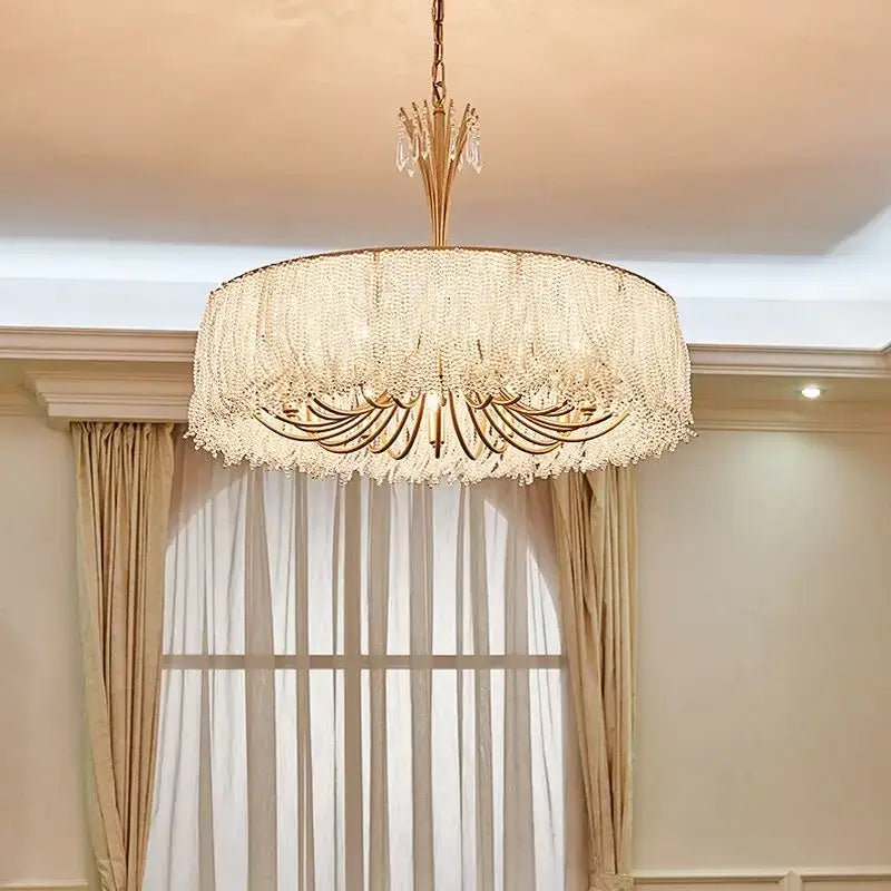 A luxurious gold-toned decorbites crystal chandelier with cascading crystal fringe for villa hall and bedroom lighting