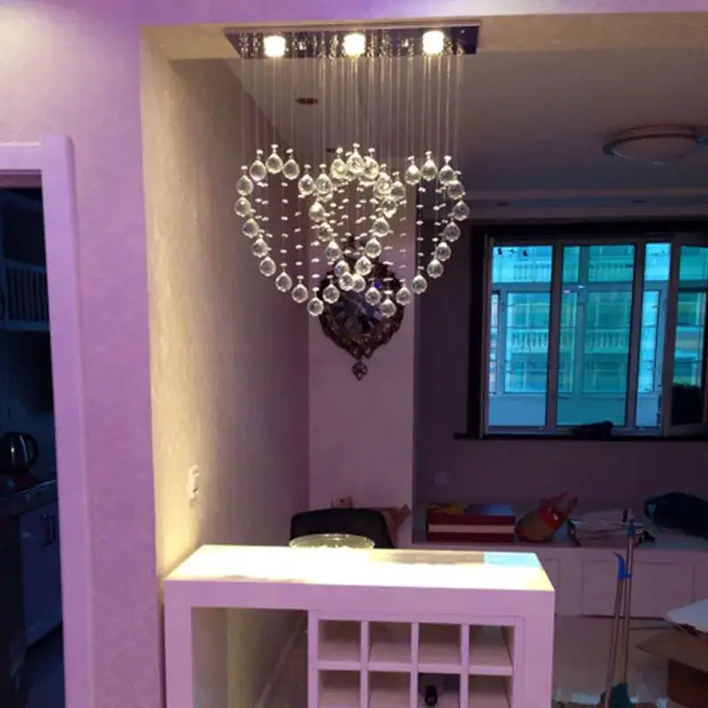 A heart-shaped decorbites crystal chandelier with dangling clear glass beads and chrome ceiling fixture for dining rooms