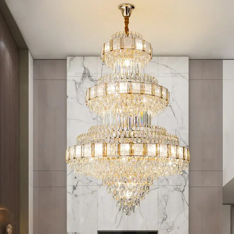 A multi-tiered decorbites crystal chandelier with gold-toned accents and cascading clear glass prisms for staircase lighting