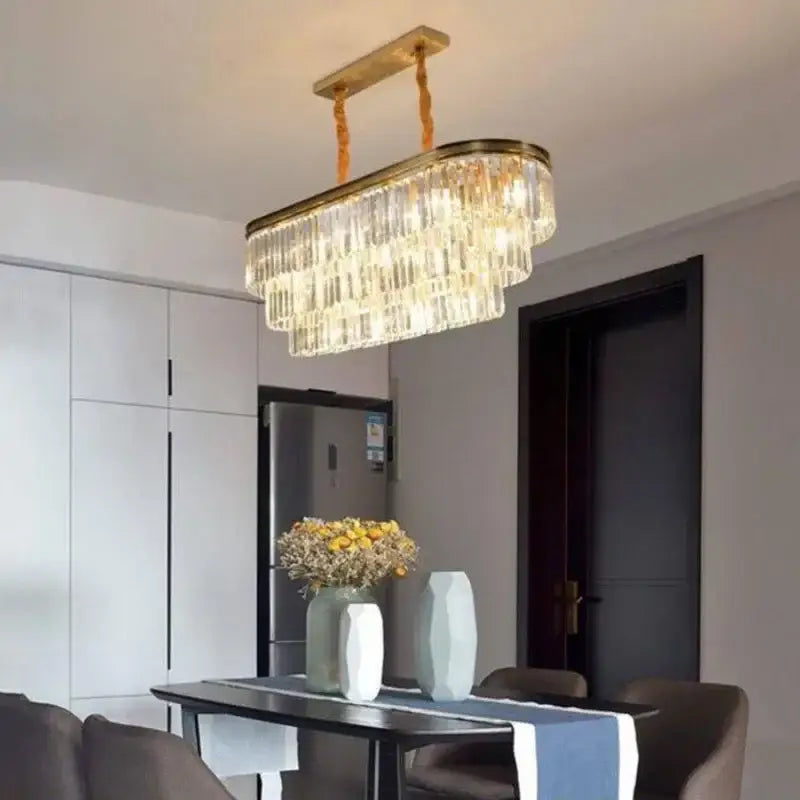 A modern decorbites crystal chandelier with gold-toned metal frame and cascading clear crystal prisms for interior lighting