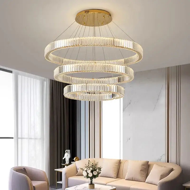 A decorbites crystal chandelier with three concentric rings of clear crystal rods and gold-toned mount for modern decor
