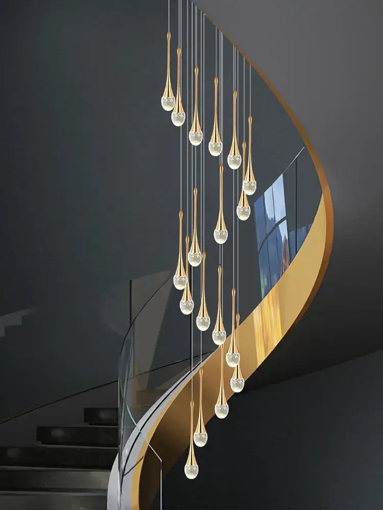 Golden teardrop-shaped decorbites crystal chandelier with crystal accents hanging above curved staircase in living room