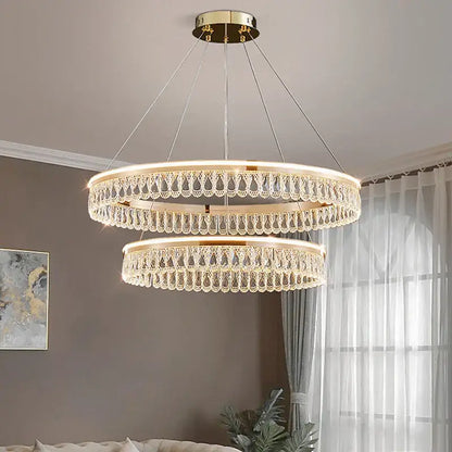 A two-tiered decorbites crystal chandelier with gold-toned mount and dangling crystal droplets for elegant living spaces