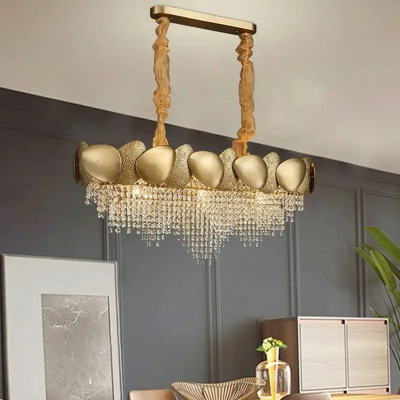 Gold-toned decorbites crystal chandelier with sculptural shell-like fixtures and cascading crystal droplets for living room