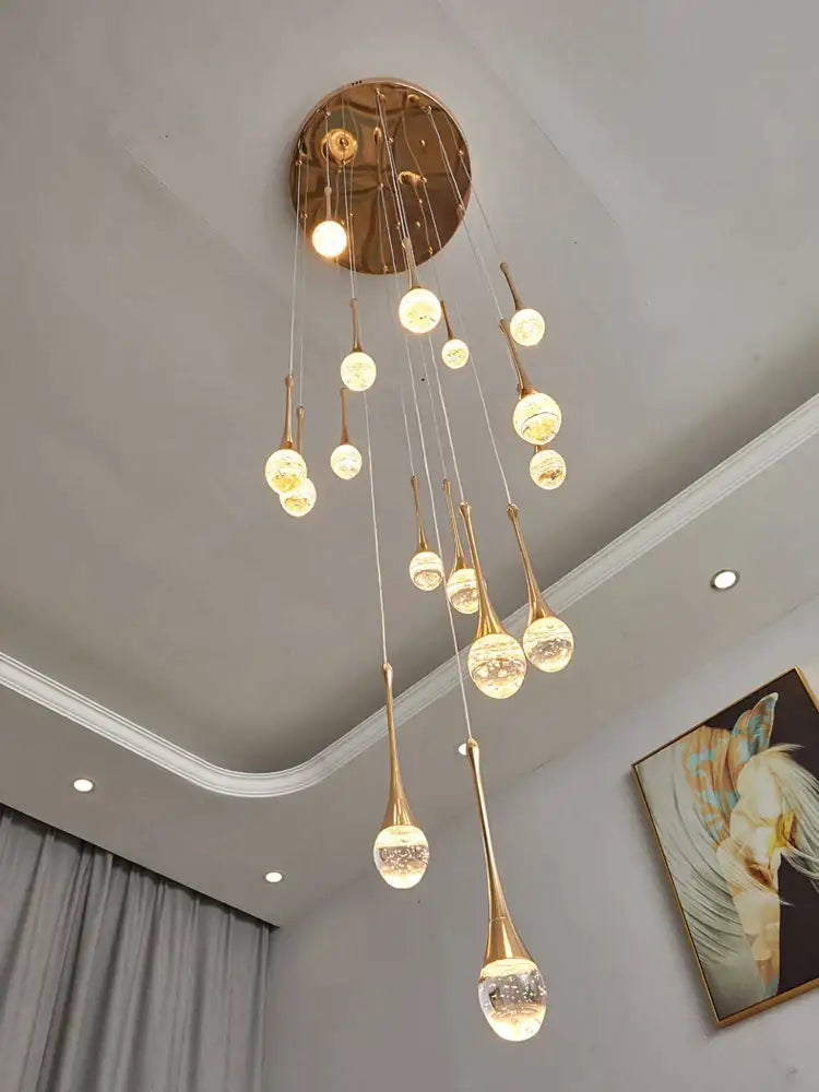Golden teardrop-shaped decorbites crystal chandelier with clear glass spheres and brass ceiling mount for staircases