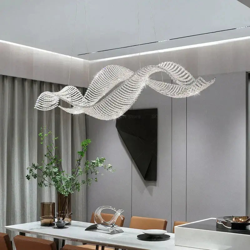 A modern wave-shaped decorbites crystal chandelier with a silver frame and clear crystals for luxury dining spaces