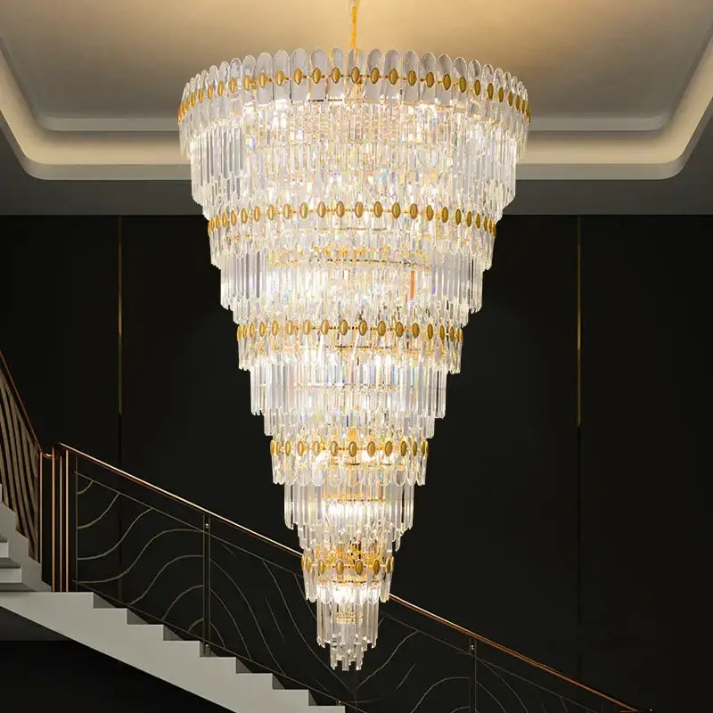 A multi-tiered decorbites crystal chandelier with gold accents and cascading clear glass prisms for luxury lighting