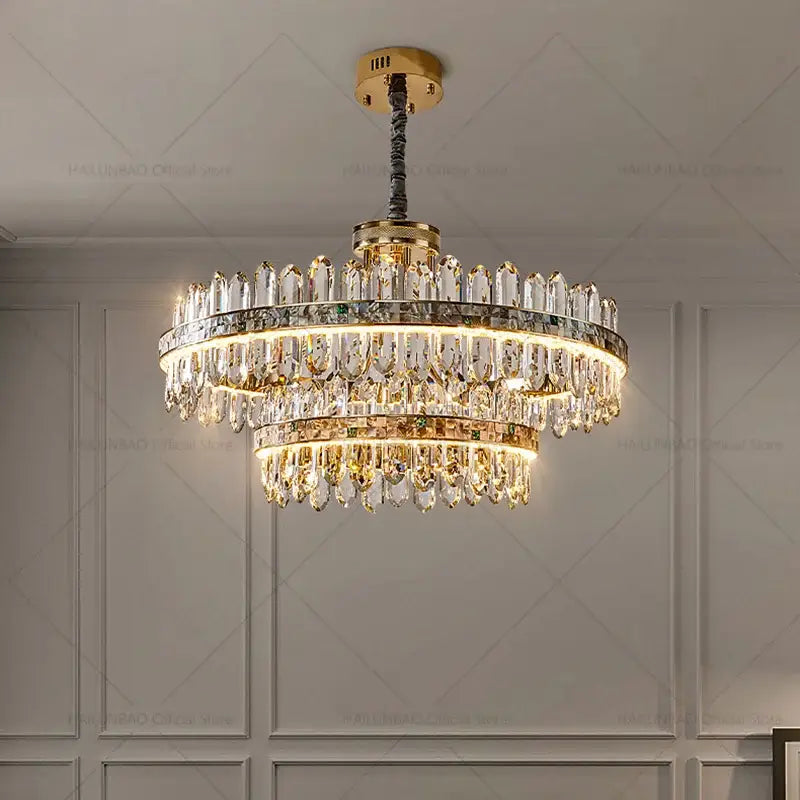 A luxurious two-tiered decorbites crystal chandelier with gold-toned metal and cascading clear crystals for living spaces