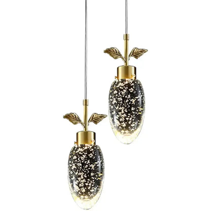 Gold-toned decorbites crystal chandelier with oval glass shades filled with sparkling particles and leafy brass stems