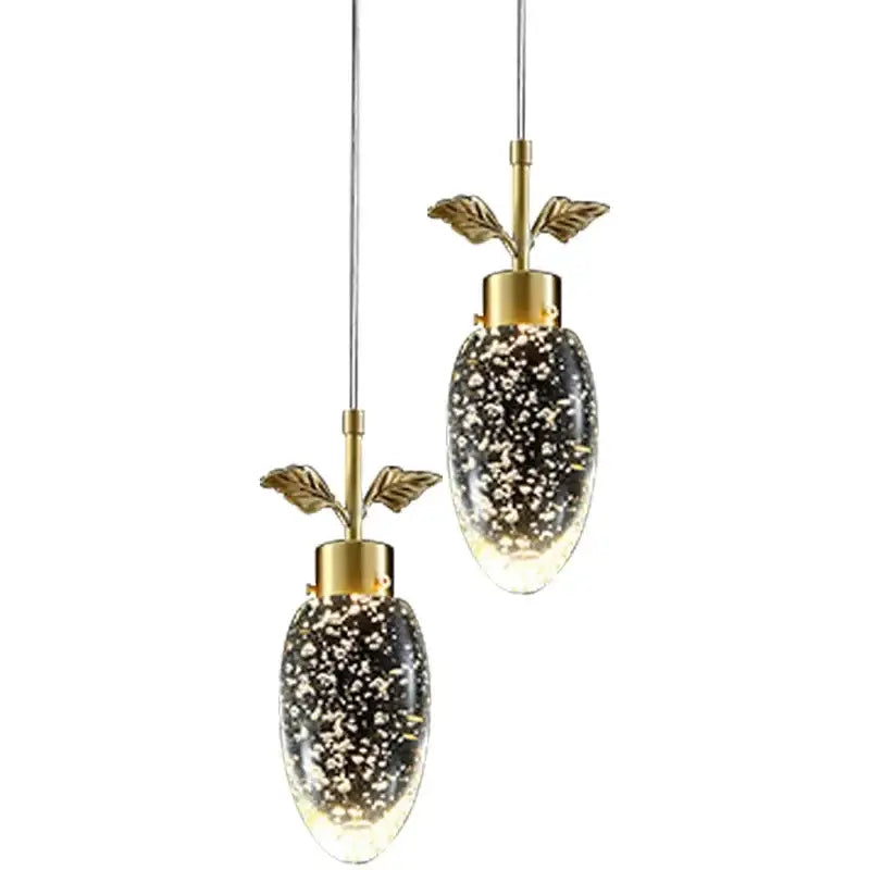 Gold-toned decorbites crystal chandelier with oval glass shades filled with sparkling particles and leafy brass stems