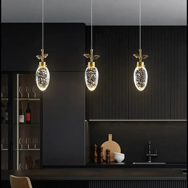 Three elegant gold-toned pendant lights with clear oval glass globes and speckles in decorbites crystal chandelier design