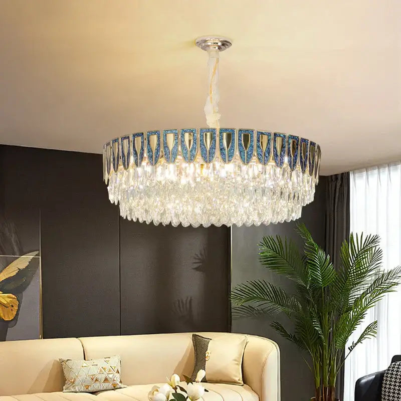 A decorbites crystal chandelier with a circular frame in blue and gold accents featuring cascading glass droplets for modern luxury lighting