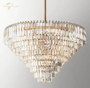 Decorbites crystal chandelier featuring a multi-tiered brass finish with cascading faceted clear crystals refracting light