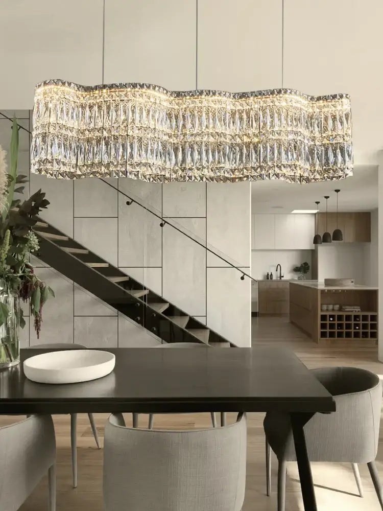 A modern DecorBites crystal chandelier pendant light with wavy gold metal frame and cascading crystal prisms