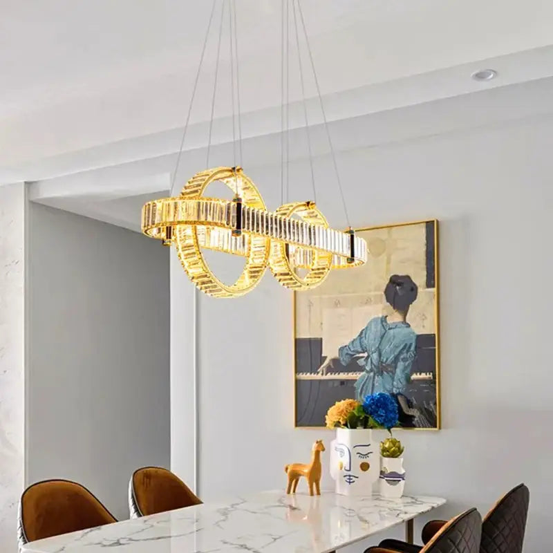 Golden modern DecorBites crystal chandelier pendant light with interlocking circular bands and crystal accents for living room