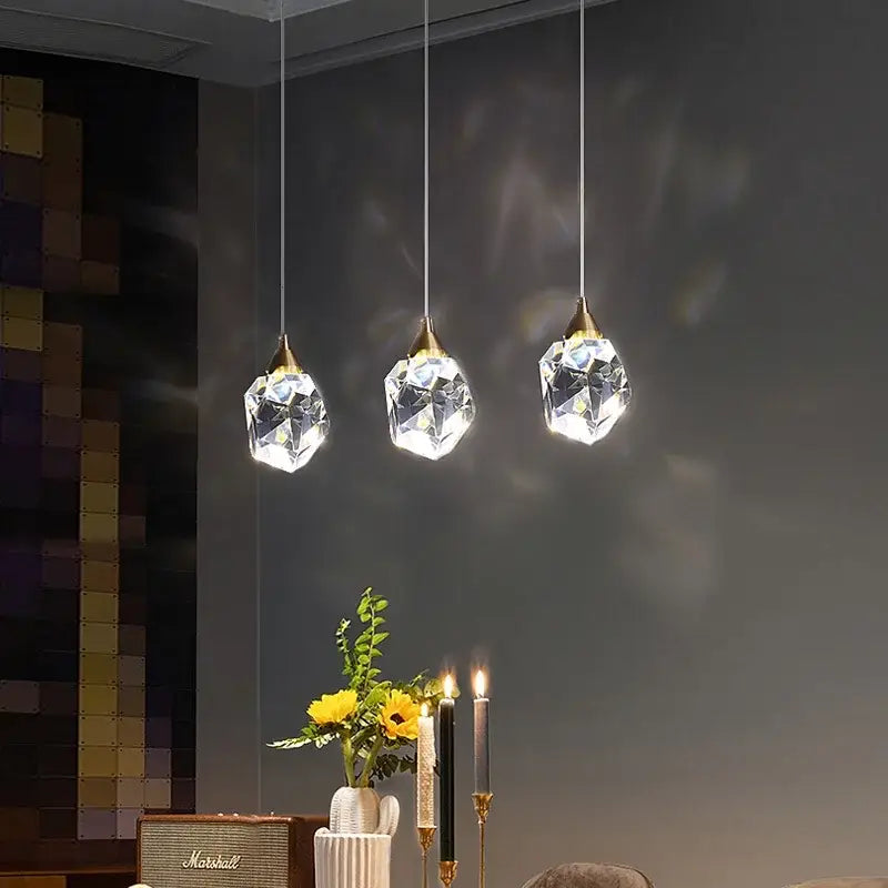 Three elegant decorbites crystal chandelier pendant lights with gold-toned fixtures and faceted glass for dining room and bedroom