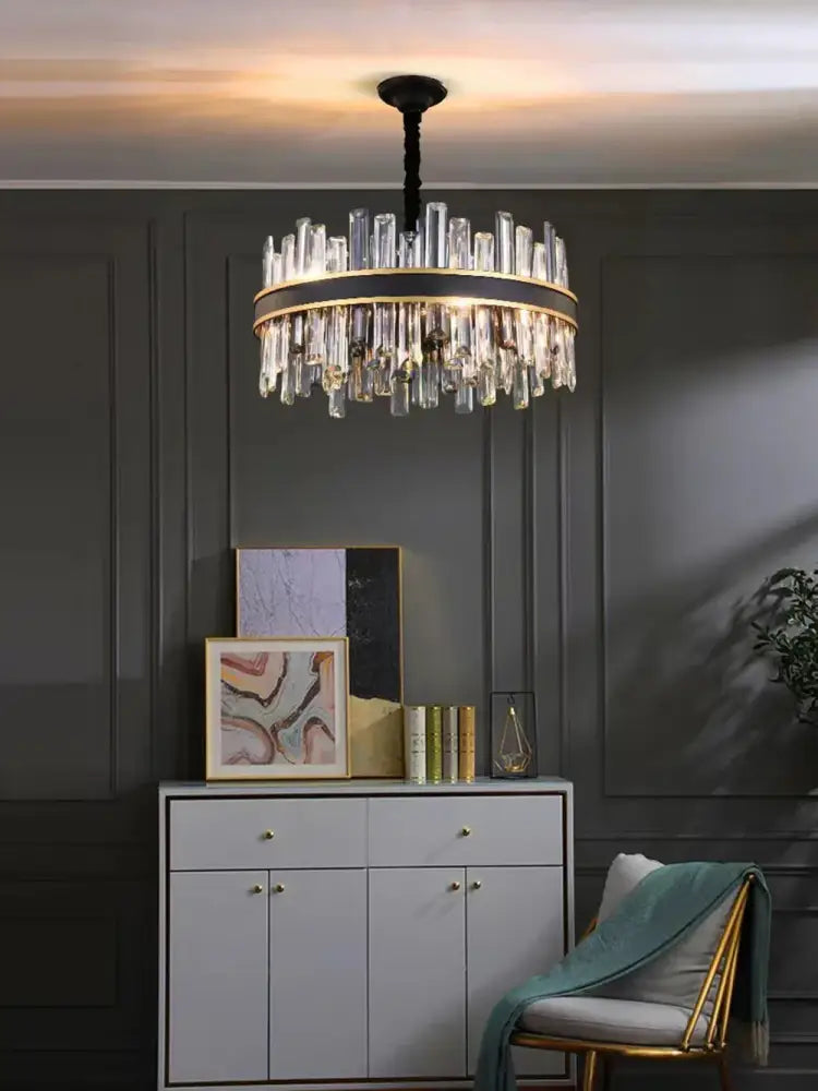 A modern decorbites crystal chandelier with a black and gold frame and cascading clear crystal prisms for luxury decor