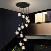 Modern black circular DecorBites™ crystal chandelier stair pendant with ten gold-topped teardrop glass stair pendant lamps