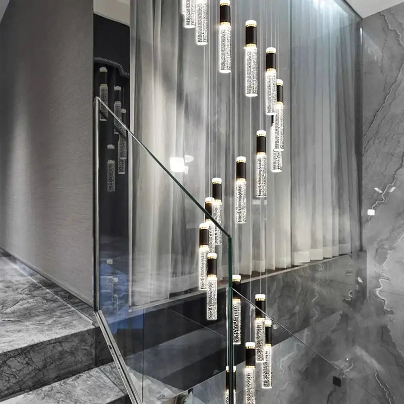 Modern decorbites crystal chandelier with cylindrical glass and black accents hanging in sleek staircase setting