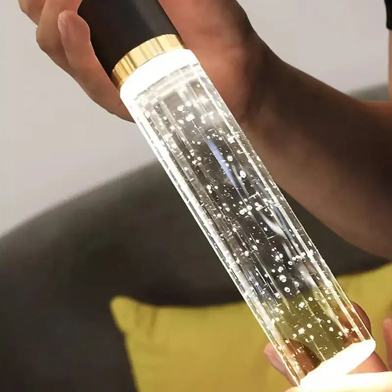 Clear cylindrical led light bottle with black and gold cap filled with glowing bubbles in decorbites crystal chandelier lamp