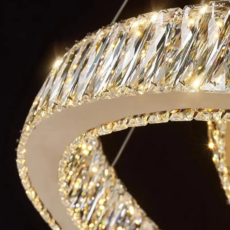 A modern decorbites crystal chandelier with a curved white frame and faceted crystals for warm living room lighting