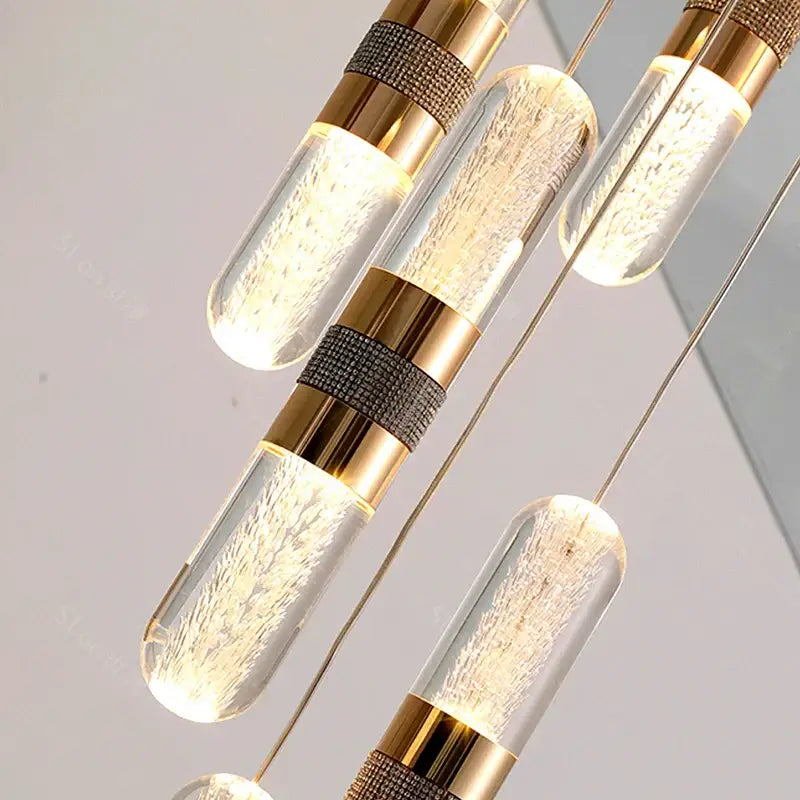 Modern gold-toned pendant lamp with clear glass cylinders and textured metallic bands in decorbites crystal chandelier stair design