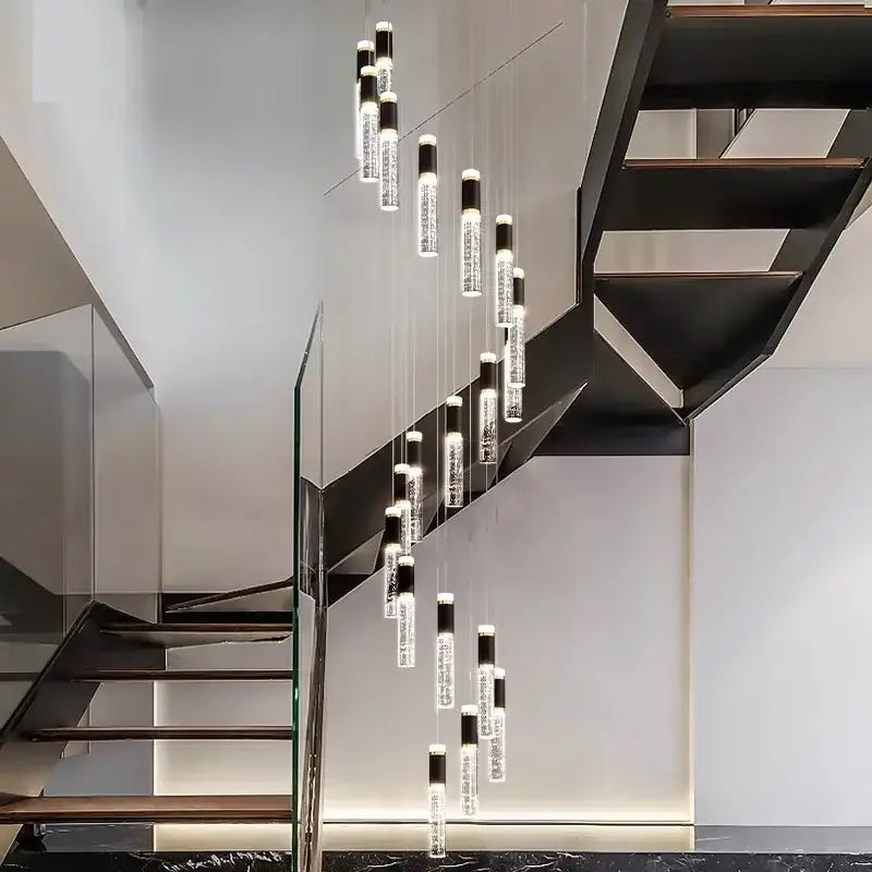 Modern decorbites crystal chandelier with clear glass cylinders and black caps above sleek staircase lighting interior