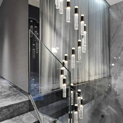 Modern cascading decorbites crystal chandelier with clear glass cylinders and black accents in a contemporary staircase