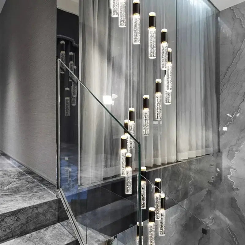 Modern cascading decorbites crystal chandelier with clear glass cylinders and black accents in a contemporary staircase