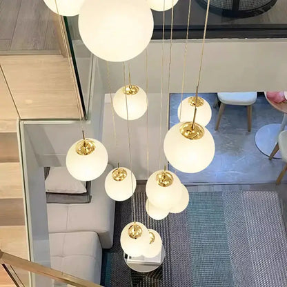 A modern DecorBites crystal chandelier stair pendant light with white glass spheres and gold metal chains for living rooms