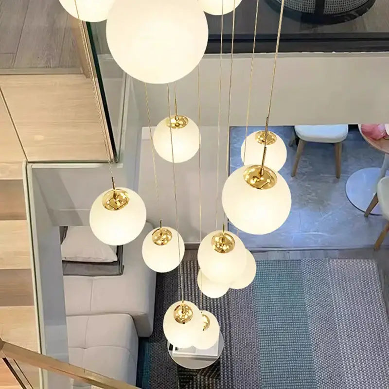 A modern DecorBites crystal chandelier stair pendant light with white glass spheres and gold metal chains for living rooms
