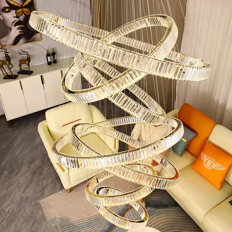 A modern decorbites crystal chandelier with interlocking crystal rings and gold accents as a stair pendant light
