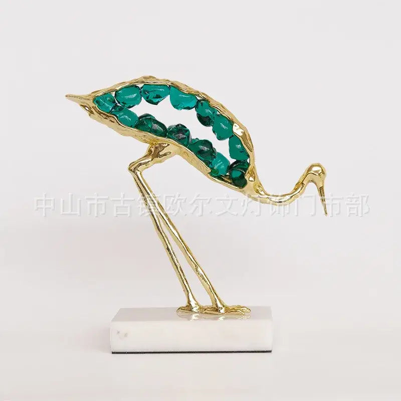 Golden decorbites crystal crane sculpture with teal gemstone body on white marble base for living room decor